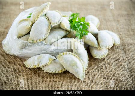 Boulettes de pâte verte crue avec persil, aneth. Boulettes crues dans un sac sur une table en bois. Banque D'Images