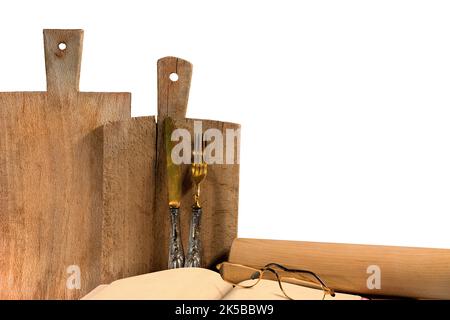 Ensemble d'ustensiles de cuisine rustiques isolés sur fond blanc. Planches à découper, couverts d'argent, livre de recettes, lunettes et broche à roulettes. Photographie. Banque D'Images