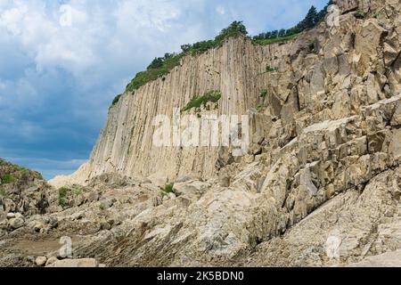 Haute falaise côtière formée par des colonnes de pierres de lave solidifiées, cap Stolbchaty sur l'île de Kunashir Banque D'Images