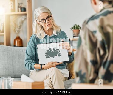 Thérapie, évaluation et psychologue discutant avec un patient d'une image d'inkblot dans un bureau. Thérapeute mature consultant avec un client Banque D'Images