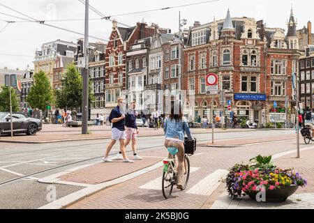 Le cycliste passe au-dessus du point de passage des zèbre, à une intersection animée du centre d'Amsterdam. Banque D'Images