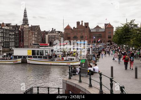 Les résidents et les touristes se promènent le long des croisières sur le canal sur le Damrak dans le centre d'Amsterdam. Banque D'Images