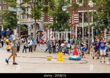 Souffleur à bulles avec des enfants heureux sur une place dans le centre d'Amsterdam. Banque D'Images