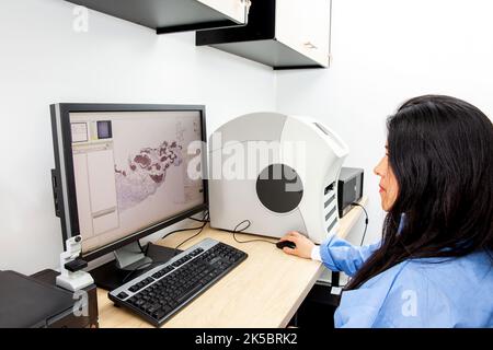 Jeunes femmes scientifiques qui numérisent des lames de microscope avec des échantillons de tissus pour des études de pathologie. Concept de diagnostic de cancer. Concept de technologie médicale. Banque D'Images