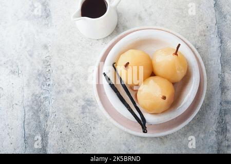 Poires. Poires pochées au sirop. Dessert traditionnel en tranches dans une assiette blanche avec des feuilles et à la maison sur un fond clair. Délicieux dessert pour Banque D'Images