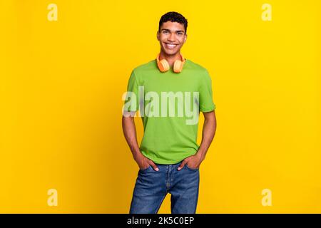 Portrait photo de jeune beau attrayant homme confiant main main poche denim porter joli cher casque sans fil isolé sur la couleur jaune Banque D'Images