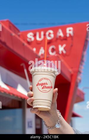 Rudyard, Montana - 2 juillet 2022 : la main tient un cocktail de chocolat au restaurant Sugar Shack du restaurant rétro à l'arrière-plan sur la chaîne (ou US-2) Banque D'Images