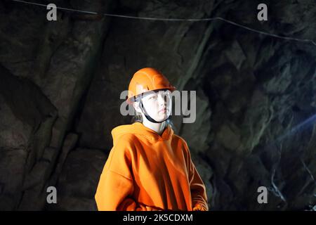 Adolescente dans un casque dans une grotte Banque D'Images