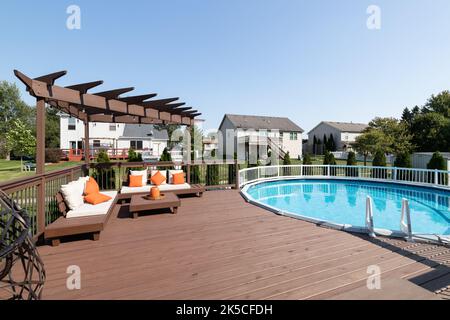 Une terrasse arrière avec une pergola sur quelques sièges et une grande piscine hors sol. Banque D'Images