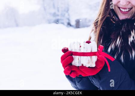 Mini-gâteau blanc eclair (dessert français traditionnel) avec ruban rouge. Une femme avec des gants rouges tient dans ses mains. Espace libre pour le texte Banque D'Images