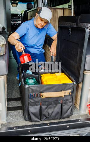 Femme stockant l'équipement de camping dans la boîte d'engrenages Radius Outfitters 500 Banque D'Images