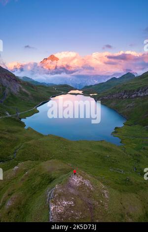 Vue aérienne d'une personne en admirant le lac Bachalpsee pendant un coucher de soleil d'été. Grindelwald, canton de Berne, Suisse, Europe. Banque D'Images