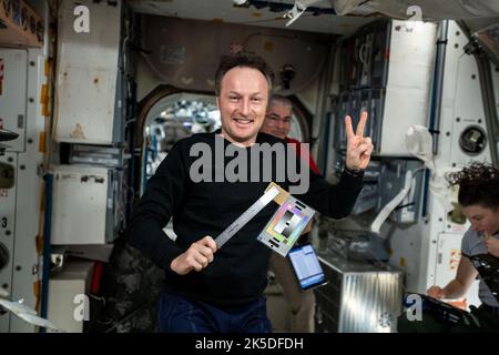 L'astronaute de l'ESA (Agence spatiale européenne) et l'ingénieur de vol de l'expédition 66 Matthias Maurer pose avec une règle et un tableau de couleurs en haut du module unité de la Station spatiale internationale. À son arrière, sont Mark Vande Hei et Kayla Barron, les ingénieurs de vol de la NASA. La règle et le graphique sont utilisés pour l'étude des carrés qui examine la façon dont les équipiers utilisent différents objets et espaces au fil du temps. Cette enquête peut fournir de l'information qui aide à améliorer la conception des futurs bateaux spatiaux et des habitats. Banque D'Images