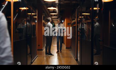 A tiré un homme contrarié en costume debout dans le couloir du bureau, tenant une boîte avec des livres et des affaires personnelles. Employé de sexe masculin quittant la société de marketing Banque D'Images