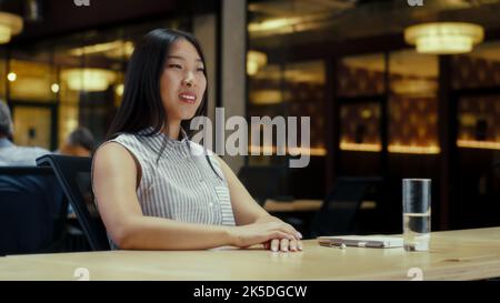 Femme asiatique parlant en ligne avec le client, ayant appel vidéo, travaillant dans le bureau moderne de la compagnie de marketing. Réunion professionnelle virtuelle. Publicité et vente de produits Banque D'Images