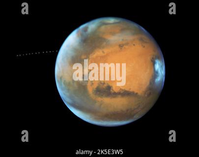 Mars. Le télescope spatial Hubble de la NASA capture également la minuscule lune Phobos lors de son périple autour de la planète Rouge. Découverte en 1877, la lune est si petite qu'elle apparaît comme une étoile dans les photos de Hubble. Phobos orbites de Mars en seulement 7hrs et 39 minutes, ce qui est plus rapide que Mars tourne. L'orbite de la lune se rétrécit très lentement, ce qui signifie qu'elle se brisera éventuellement sous l'attraction gravitationnelle de Mars, ou s'écrasera sur la planète. Hubble a pris 13 expositions sur 22 minutes pour créer une vidéo en time-lapse montrant le chemin orbital de la lune.version optimisée d'une image originale de la NASA. Crédit: NASA Banque D'Images