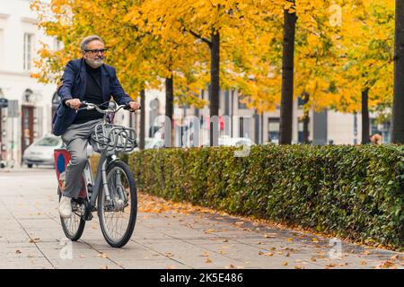 Couleurs de l'automne. homme de 60 ans heureux aux cheveux gris sur la chaussée dans son parc préféré de la ville. Loisirs actifs dans la nature. Photo de haute qualité Banque D'Images