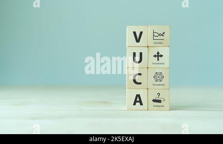 VUCA et gestion stratégique. Cubes en bois avec icône VUCA et texte; volatilité, incertitude, complexité, ambiguïté avec fond gris. Gestion intelligente Banque D'Images