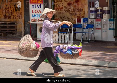 Un motard vietnamien portant un chapeau de bambou portant un pannier dans la rue, Hai Phong, Vietnam Banque D'Images