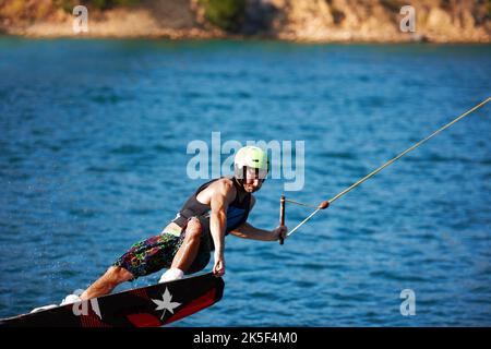 Un jeune homme portant un helmut et un gilet de sauvetage sur un lac Banque D'Images