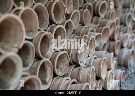 Gros plan des piles de pots de fleurs de terre cuite anciens et altérés dans le hangar de jardinage Banque D'Images