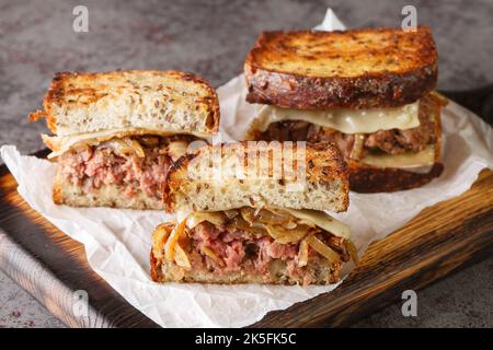 Le sandwich Patty Melt est une variante du cheeseburger américain classique utilisant du pain croustillant, du fromage et des oignons tendres sur le panneau en bois du Banque D'Images