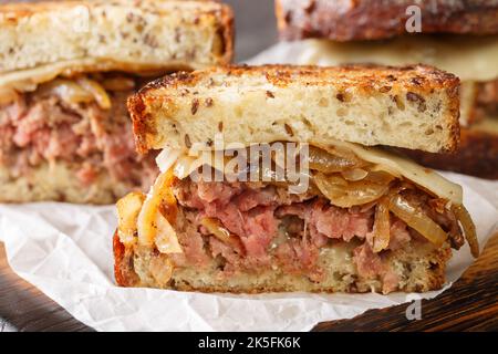 Sandwich Patty Melt composé d'une couche d'oignons caramélisés, de fromage et de patty hamburger entre le pain grillé et le panneau en bois de la table. H Banque D'Images