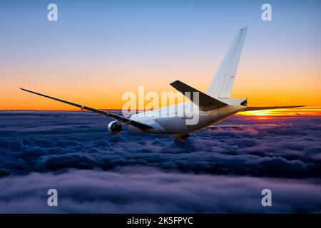 L'avion de ligne large blanc pour passagers vole dans le ciel du coucher du soleil Banque D'Images