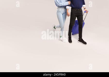 Homme et femme voyageur tenant les mains gentiment marcher avec une valise bleue isolée sur fond blanc Banque D'Images