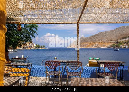 Vue panoramique sur le petit havre de l'île de Symi. Village avec Street Cafe et maisons colorées situé sur le rocher. Banque D'Images