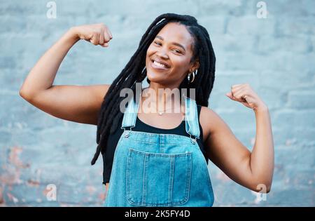 Bonne femme noire, sourire portrait et puissance musculaire, force et confiance poser sur le fond du mur. Fière femme africaine flexion biceps, muscles et Banque D'Images