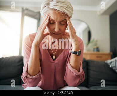 Femme âgée souffrant de maux de tête, de stress et de dépression tout en se sentant fatiguée, surburnout et inquiète sur le canapé à la maison. Anxiété et triste femme avec mental Banque D'Images