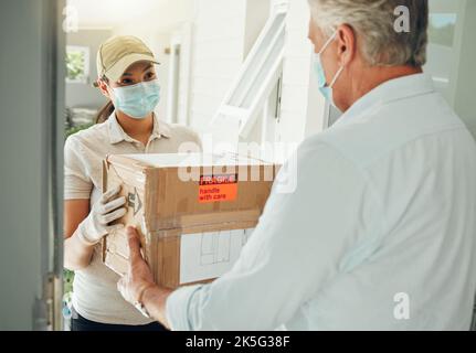 Le travailleur de la livraison en ligne, pendant la pandémie de covid ne ecommerce transport de boîte à porte et avec un masque sur le visage. Commerce électronique industrie du shopping, détail Banque D'Images