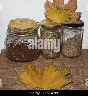 Bouteilles en verre avec café moulu et thés aux feuilles jaunes. Sur la table. Automne. Banque D'Images