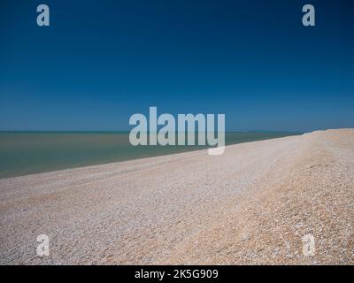 L'étendue ouverte de la plage déserte de galets à Dungeness, Kent, Royaume-Uni. Pris par une journée ensoleillée en été. Banque D'Images