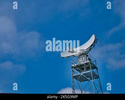 Une antenne parabolique blanche montée sur une tour de châssis en acier. Pris par une journée ensoleillée en été. Banque D'Images