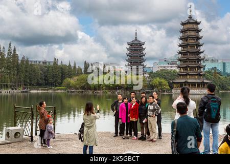 Guilin, Chine. Les visiteurs qui prennent des photos dans les jardins le long Shan (FIR) Lac. Soleil et lune de pagodes en arrière-plan. Banque D'Images