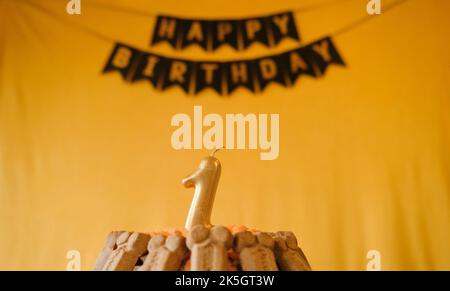 Concept de l'anniversaire du chien. Gâteau pour animaux de compagnie fait de biscuits en forme d'os de viande, carottes et nombre d'or de 1 bougie. Drapeaux noirs avec inscription ha Banque D'Images