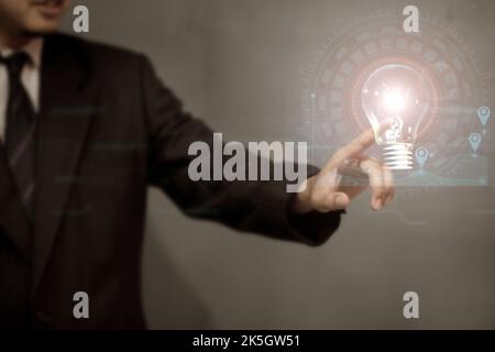 Homme d'affaires tenant une ampoule avec un graphique montrant l'augmentation de la consommation d'électricité. Banque D'Images