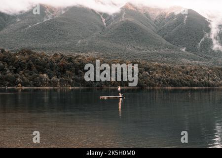 jeune homme caucasien sans cheveux dans les troncs de natation et sur la plate-forme en bois du lac clair avec ses bras croisés sur le point de sauter dans l'eau pour un Banque D'Images