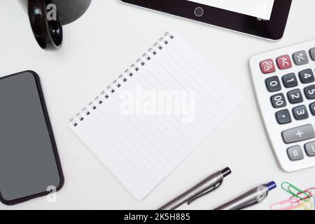 Vue rapprochée d'un espace de travail portable avec tablette et papeterie sur la table dans un espace de travail commun. Banque D'Images