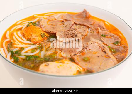 Bun Bo Hue, soupe vietnamienne de nouilles de riz au bœuf épicé, nourriture vietnamienne isolée sur fond blanc, gros plan Banque D'Images