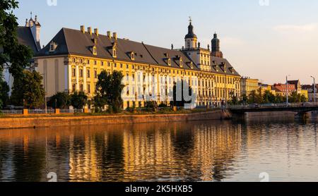 Wroclaw, Pologne - 19 juillet 2022: Quartier historique de la vieille ville avec l'université de Wroclaw et la rue Grodzka remblai au coucher du soleil sur la rivière Warta Banque D'Images