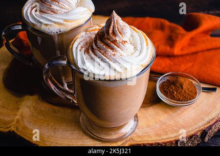 Chocolat chaud aux épices de citrouille recouvert de crème fouettée : mugs de chocolat chaud nappés de crème chantilly et d'épices de citrouille Banque D'Images