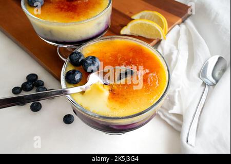 Crème brûlée aux myrtilles et aux oranges : dessert crème anglaise avec une garniture de sucre caramélisé craquelé Banque D'Images