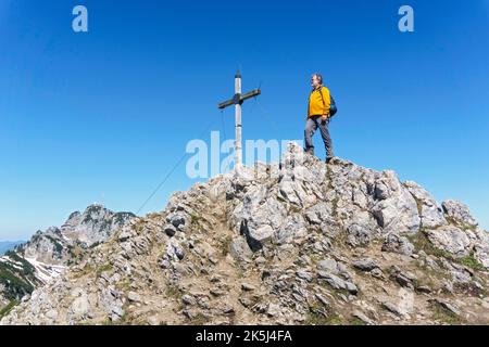 Randonneur, senior, 63 ans, se reposer sur le sommet de Wildalpjoch, Wendelstein à l'arrière, Bayrischzell, Mangfall Mountains, haute-Bavière, Allemagne Banque D'Images