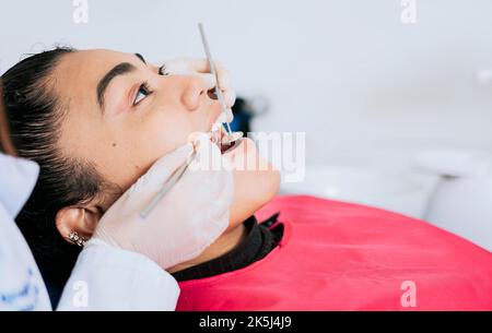 Gros plan d'un dentiste professionnel nettoyant les dents de la patiente, gros plan d'un spécialiste dentaire nettoyant les dents d'un patient. Vue latérale du dentiste Banque D'Images