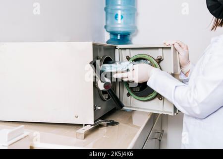 Dentiste avec stérilisateur dentaire, dentiste mains stérilisant ses outils, dentiste avec autoclave dentaire, gros plan du dentiste avec stérilisateur vapeur. Mains Banque D'Images