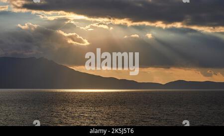 Ciel nuageux et spectaculaire en soirée, rayons du soleil se brisant à travers les nuages, reflet du soleil sur la mer, coucher de soleil, lumière du soir, péninsule de Rodopou, Gramvoussa Banque D'Images