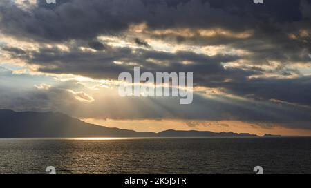 Ciel nuageux et spectaculaire en soirée, rayons du soleil se brisant à travers les nuages, reflet du soleil sur la mer, coucher de soleil, lumière du soir, péninsule de Rodopou, Gramvoussa Banque D'Images